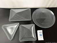 Set of 4 Lausitzer Glas Kristall serving dishes with white optical line designs on clear glass, shown together with MaxSold tag.