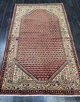 Full view of the rectangular Arak Persian rug showing its orange central field with Boteh pattern and beige decorative borders.