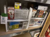 Shelf with multiple boxes and loose assorted light bulbs, various brands and types visible, stacked in bins