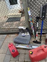 Car floor mats stacked on the ground with red gas canisters, umbrella, hand tools, and packaged 4 Ton Cable Puller.