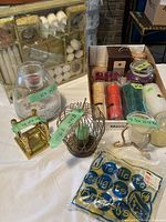 Assorted candles and multiple candle holders, including pillar candles, tealight candles, and various holder styles in glass, metal, and woven materials.