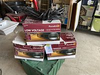 Three boxes of Paradise Low Voltage 12V deck and stair lighting kits stacked, showing the packaging and wires included in the lot.