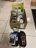 Overview photo of the box containing electrical supplies laid on tile floor