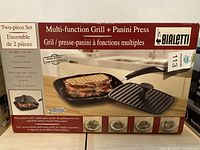 Front box view showing product name, images of grill with panini, and product benefits including healthy low-fat cooking and easy to clean