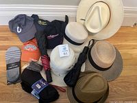 Overview of lot showing hats, socks, and umbrellas including brimmed hats, baseball hats, socks, and umbrellas clustered on floor.