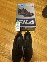 Pair of black FILA waterproof shoes size 13 with the box on the floor.