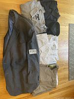 Photo of 5 dress shirts laid flat alongside dress pants and a blazer on a wooden floor.