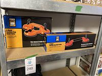 Two boxed Power Fist dent pullers on metal shelving: a 3-head orange suction cup model and a 2-head red suction cup model.