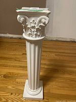 Front view of the white decorative pedestal column showing fluted shaft and ornate top design.