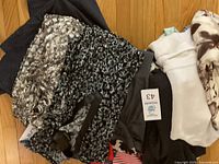 Variety of women's clothing including patterned shorts and tops laid out together, showing clothing tags and a range of colors and fabrics.