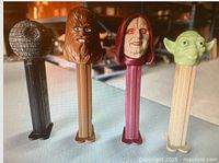 Photo showing Death Star, Chewbacca, Emperor Palpatine, and Yoda Pez holders in a row, highlighting the detailed character heads and colored stems.