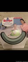 Box showing brand Bumbo and image of baby in green seat with parent.
