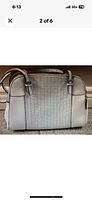 Close up of white Guess handbag second angle highlighting perforated front panel and structure