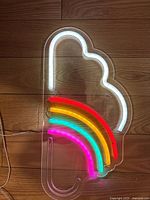 Front view of the neon cloud and rainbow light sign showing the white cloud outline and colorful rainbow beneath on a clear plastic backing.