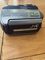Compact silver and black JVC Everio GZ-MG130 camcorder with 34x optical zoom and hybrid flash memory label visible on the side.