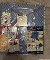 Another front angle of the pocket journal kit in packaging, showing the label and the assortment of designs on the cards inside.