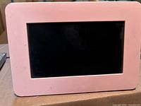 Front view of pink Samsung digital photo frame with display screen visible.