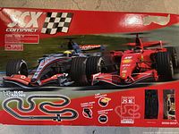 Box art showing two Formula 1 style slot cars with SCX Compact branding and slot racing track schematic.