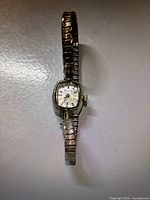 Front view of the vintage Bulova watch with metal expandable bracelet band and rectangular gold tone bezel.