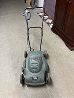 Full view of green Black and Decker electric lawn mower showing handle and wheels.