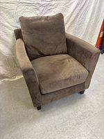 Front angle view of the brown armchair showing seat cushion, back cushion, armrests, and wooden legs.