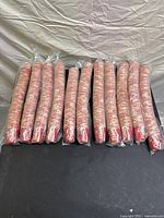 Multiple packs of Coca-Cola branded disposable paper cups with New Coke logo, shrink-wrapped and stacked vertically.