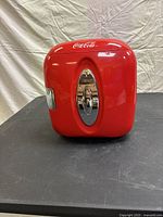 Front view of the red Coca-Cola mini fridge showing rounded edges, chrome handle, and Coca-Cola logo.