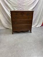 Front view of the wooden dresser showing five drawers and brass drop pulls, standing on cabriole legs with scalloped apron.