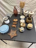 Full lot overview showing all items on black table surface including pottery, glass, and metal decorative pieces.