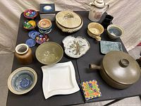 Full collection of various ceramic dishes, bowls, plates and decorative items arranged on a black table