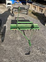 Full view of tow-behind dethatcher on gravel surface with shadow