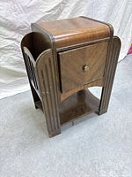Front and left side view of wooden vintage side table showing rectangular veneered top, single door storage with chevron pattern, stepped vertical ridges on sides, open shelf base, and short block legs.