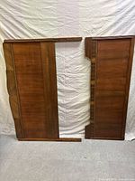 Headboard and footboard of a traditional brown wood double bed set against white backdrop.