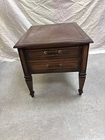 Front view of the traditional dark wood side table showing drawers and tapered legs
