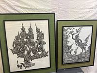 Two traditional black and white framed prints against a white fabric background, showing overall lot contents.