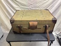 Full view of the large rectangular Finnigans suitcase made of green canvas with brown leather straps and corner protectors. Shows aged leather and patina.