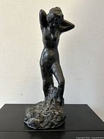 Front view of bronze nude female sculpture with raised arms, signed AMR 1966.