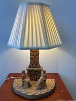 Full lit lamp showing carved wood folk art scene with couple and stone fireplace