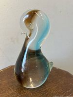 Side view of chalet art glass chick sculpture showing fluid curves, small beak, and color swirls in the glass.