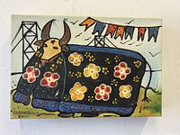 Frontal view of the oil painting depicting a stylized bull adorned with colorful floral patterns and background decorations.
