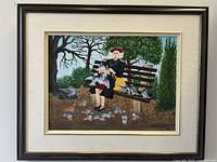 Framed oil painting showing elderly woman on bench with pigeons in park setting