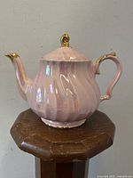 Side view of pink swirl lustreware Sadler teapot showing body, spout, handle, and lid with gold accents.