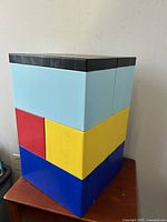 Front and side views of the modular building block table showing vibrant colorful large interlocking blocks in black, light blue, yellow, red, and blue, 19 inches tall.