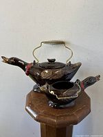 Full view of the mallard duck shaped ceramic teapot and matching cream jug on a wooden stand, showing their shape and finish.
