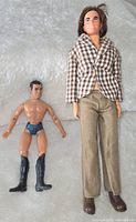 Barbie Ken doll dressed in checkered jacket, beige pants, brown shoes beside Mego Captain Kirk action figure with blue underwear and black boots.