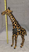 Front side view of the leather giraffe with a measuring stick showing about 20 inches tall.