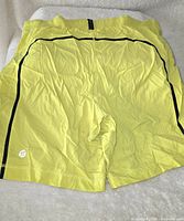 Full back view of yellow Lululemon shorts with black piping and elastic waistband.