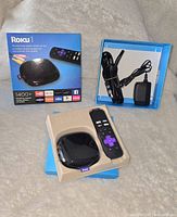 Photo of the Roku 1 streaming player with remote control and power adapter inside the open box packaging.