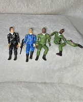 Four A-Team figures laid on grey fabric, including 3 complete figures and 1 Mr. T figure separated into parts.