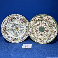 Two Royal Worcester hand painted cabinet plates shown standing side-by-side on a blue cloth background